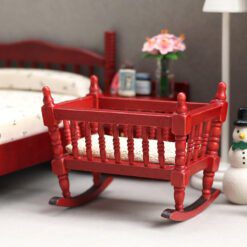 Miniature wooden rocking cradle for dollhouse nursery.