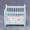 Miniature blue baby crib for dollhouse nursery.