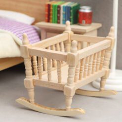 Miniature wooden rocking cradle for dollhouse nursery.