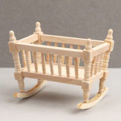 Miniature wooden rocking cradle for dollhouse nursery.