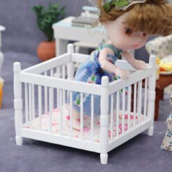 Miniature white baby crib for dollhouse nursery.