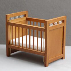Miniature wooden baby crib with mattress for dollhouse nursery.