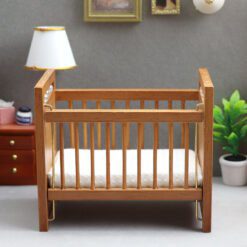 Miniature wooden baby crib with mattress for dollhouse nursery.