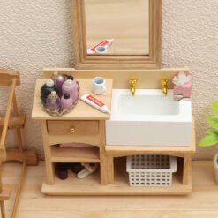 Miniature wooden bathroom sink cabinet with white sink and gold faucets for dollhouses.